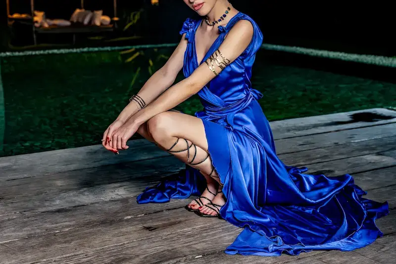 Luxury escort in Denmark in a blue evening gown by the water at night, Top Companions